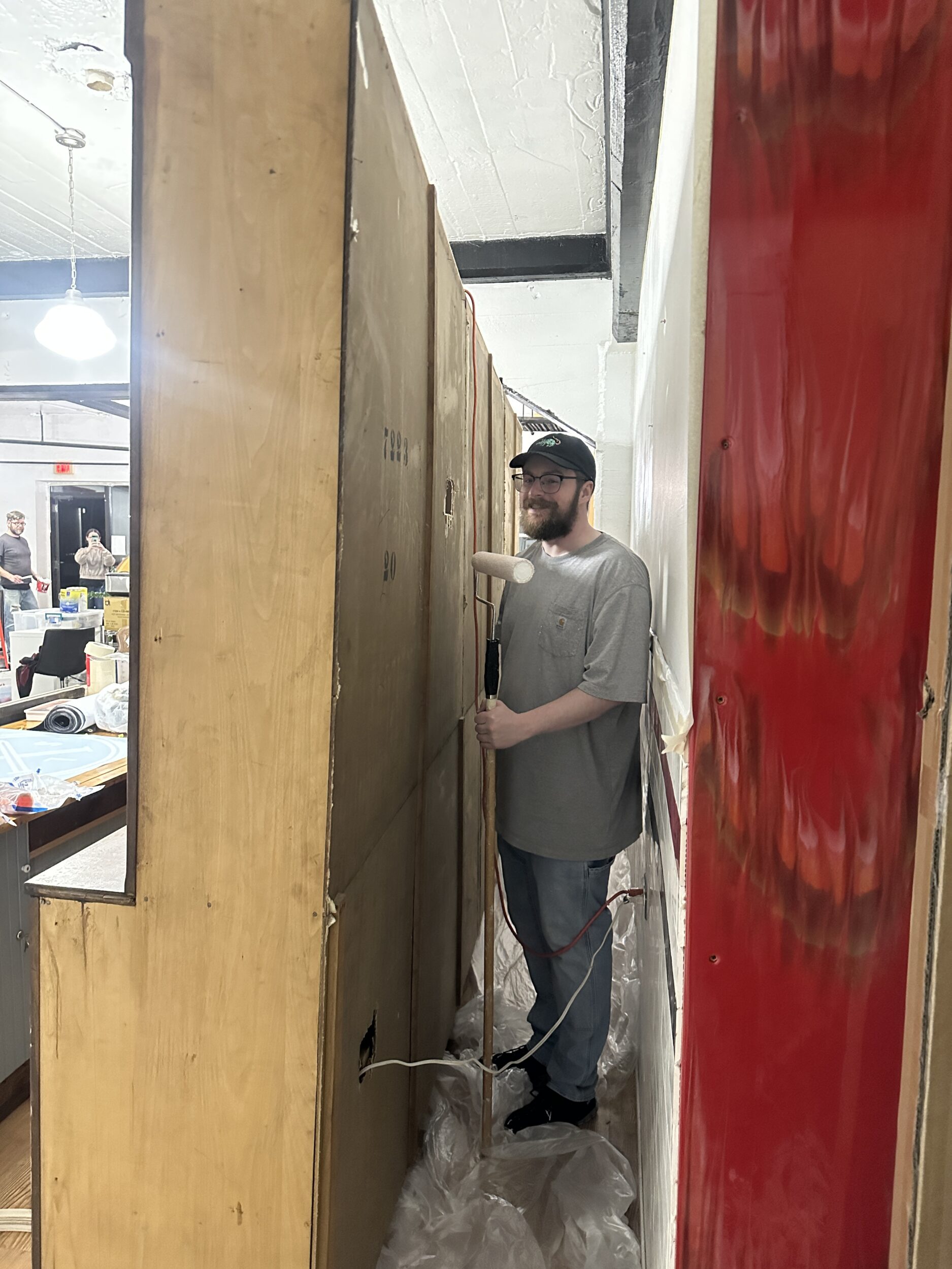 person smiling and holding a paint roller