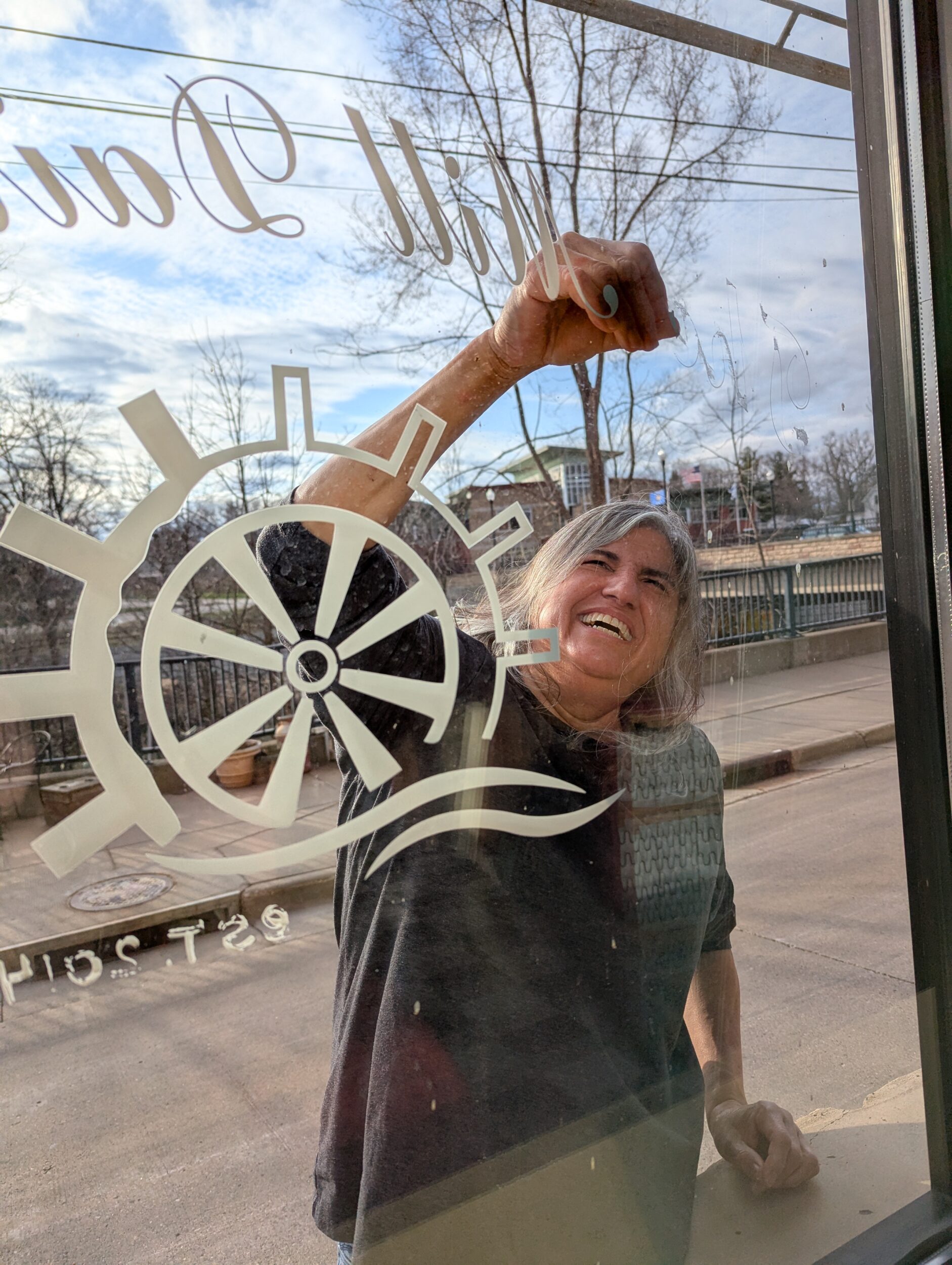person smiling and removing a decal from a window