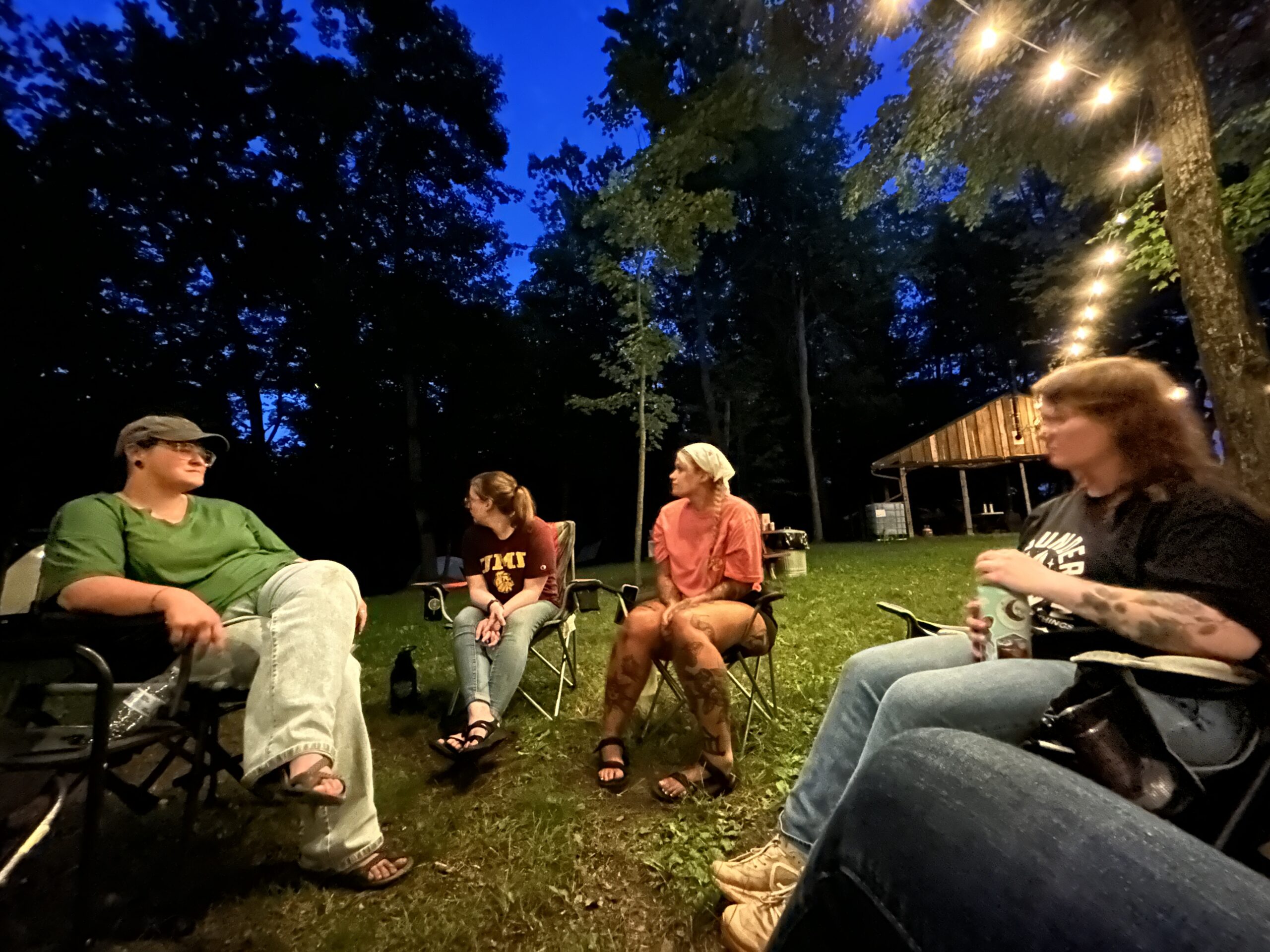 group of people sitting around campfire at night